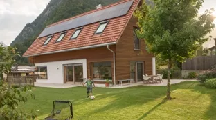 Boy playing football in front of house with pv modules